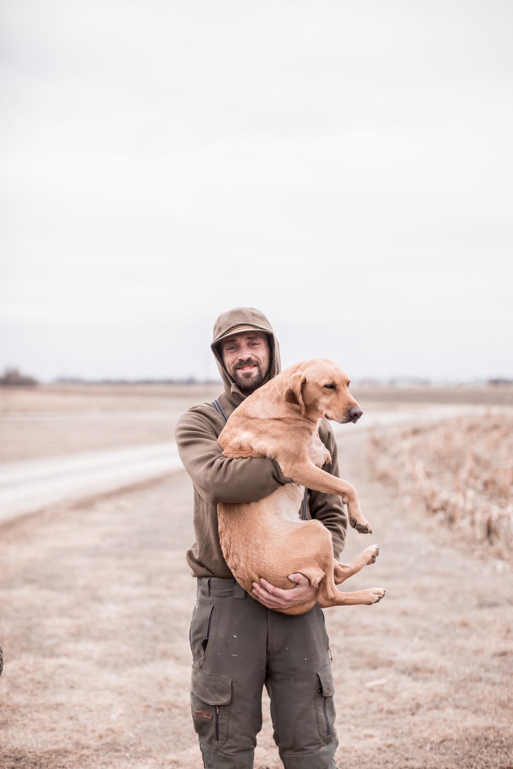 Ben Baker holding a yellow Labrador in the field