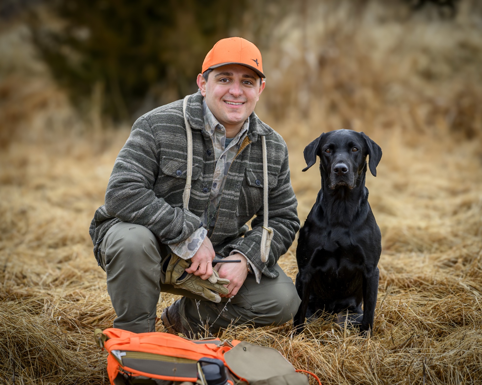 Hunter kneeling beside a black Labrador