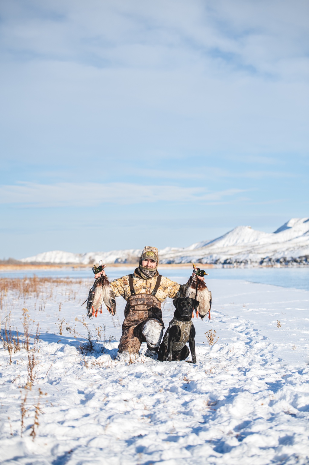 Rockin’ B Huck, a black Labrador, with a hunter after a snowy waterfowl hunt